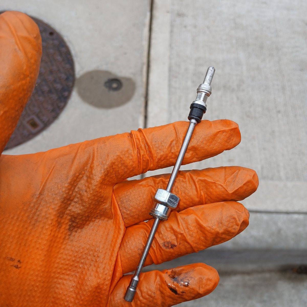 A second worn part from the same job, held in an orange-gloved hand